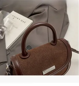 Détail d'un sac à main en daim avec poignée ronde et barre métallique argentée