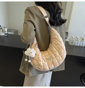 Détail du sac demi-lune matelassé avec bandoulière réglable et breloque nuage