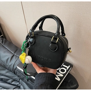Détail du mini sac noir texture lychee avec logo embossé et breloques sportives