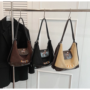 Dettaglio di tre borse hobo in pelle scamosciata marrone, nera e beige ricamate
