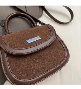 Vue détaillée du sac besace marron montrant le cuir mat et la boucle métallique
