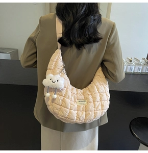 Détail du sac croissant matelassé pêche avec breloque peluche et large bandoulière porté