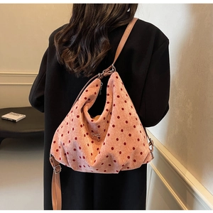 Pink polka dot tote bag featuring a silver metal bow detail shown on a model