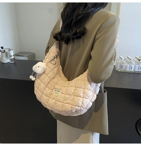 Détail du sac à bandoulière matelassé abricot clair avec breloque peluche et logo