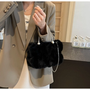 Detail of black faux fur handbag featuring silver chain strap and large pearl closure