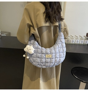Sac croissant matelassé bleu clair avec charme nuage porté sur un trench-coat kaki