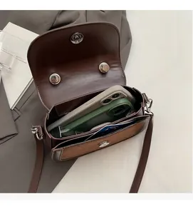 Détail de l'intérieur spacieux du sac besace en cuir marron avec deux smartphones