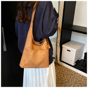 Close-up of retro brown suede tote bag with two large front pockets and shoulder strap