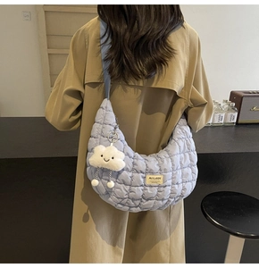 Détail d'un sac dumpling matelassé lavande avec charm nuage porté par un mannequin
