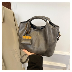 Close-up of retro dark gray faux leather tote bag with orange mini bag pendant