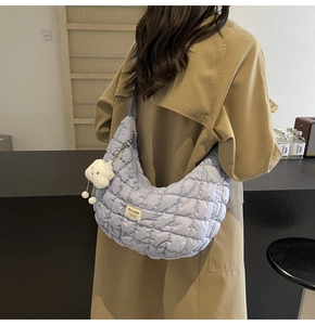 Détail du sac demi-lune matelassé bleu clair avec un joli pendentif nuage blanc