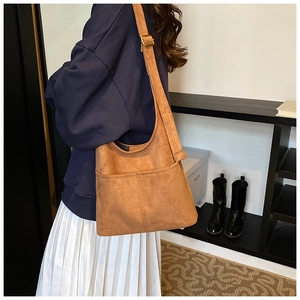 Detail view of large brown faux suede hobo bag with adjustable strap and wide front pocket