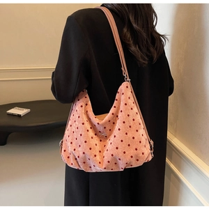 Polka dot hobo bag in pink corduroy with silver bow worn by a model on the shoulder