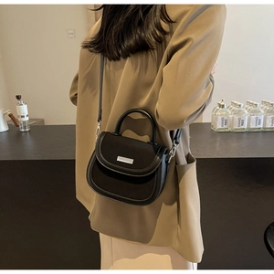 Détail du sac selle en cuir mat noir minimaliste avec boucle argentée et bandoulière