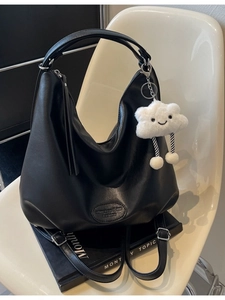 Grand sac cabas noir en cuir PU avec pendentif nuage posé sur une chaise blanche design