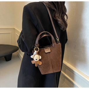Brown frosted leather bucket bag featuring a cute monkey charm and leather shoulder strap