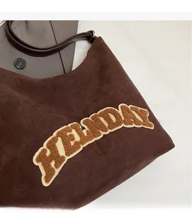 Dettaglio della borsa tote in pelle scamosciata marrone con applicazione HOLIDAY