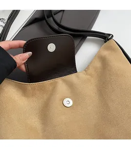 Dettaglio della chiusura magnetica in argento su borsa a patta in pelle e camoscio kaki