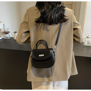 Vue détaillée d'un sac selle noir rétro avec boucles argentées et une poignée supérieure chic