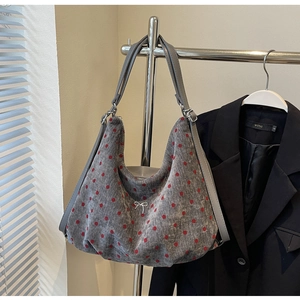 Detail of grey polka dot hobo bag with silver metal bow and canvas texture