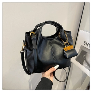 Detail of black vintage faux leather bucket bag with gold hardware and mini pouch charm