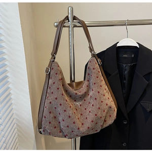 Detail of grey tote with red polka dots featuring a silver bow and leather strap