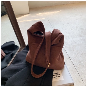 Retro brown suede tote bag with matte finish and dual straps on a magazine background