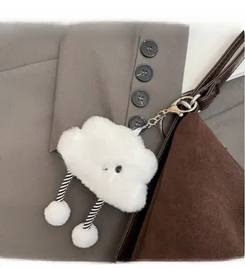 Dettaglio di un ciondolo a nuvola bianca in peluche appeso a una borsa marrone scuro