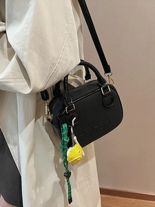 Minimalist black leather crossbody bag with green knot and duck charms in fashion style