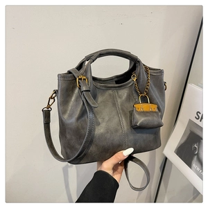 Detail of vintage grey leather tote with round handles and mini coin purse charm