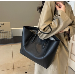 Minimalist black faux leather tote bag styled with a beige trench coat for a chic daily look