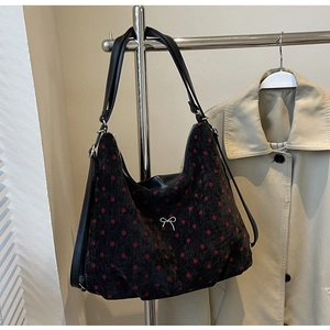 Close-up of black corduroy hobo bag with red polka dots and silver bow detail