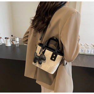 Chic beige canvas bucket bag with black leather trim and cute puppy charm detail