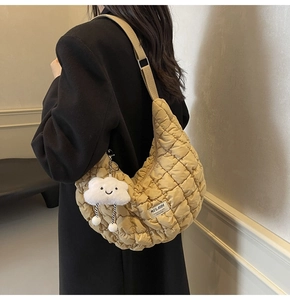 Sac croissant beige matelassé avec charme nuage porté sur une veste de costume