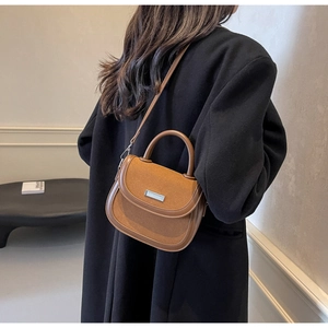Sac bandoulière marron caramel avec empiècement en daim et boucle métal sur manteau noir