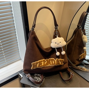 Dettaglio della borsa tote in pelle scamosciata marrone con ricamo giallo e ciondolo