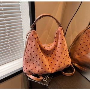 Detailed close-up of pink polka dot velvet hobo bag with small metal bow pendant