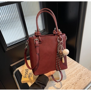 Detail of burgundy PU leather bucket bag with creative baseball charm and straps