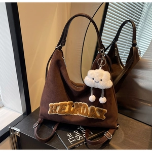 Dettaglio della borsa tote in pelle scamosciata marrone con ricamo HELNDAY e ciondolo nuvola