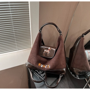 Dettaglio della borsa vintage in pelle scamosciata marrone con ricamo di cane e base in pelle