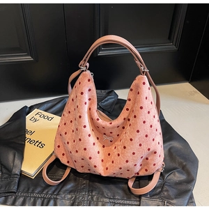 Close-up of pink polka dot bag with silver bow charm on a black leather jacket