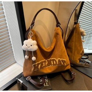 Dettaglio della borsa hobo in pelle scamosciata marrone con lettere gialle in peluche