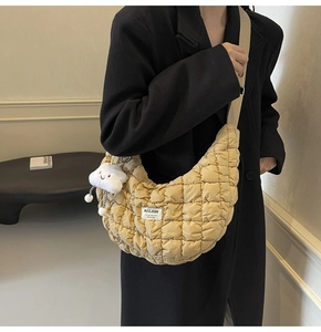Gros plan du sac bandoulière beige matelassé en demi-lune avec breloque nuage