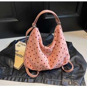 Close-up of pink polka dot hobo bag with a silver metal bow detail on a black leather jacket