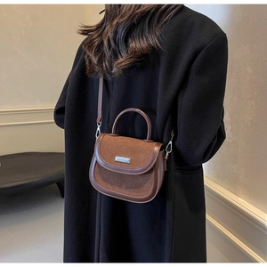 Détail d'un sac besace marron vintage avec patchwork en daim et poignée ronde