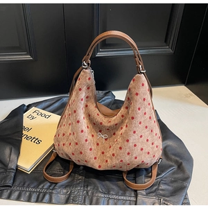 Polka dot hobo bag with red bow buckle shown next to a black jacket and art books