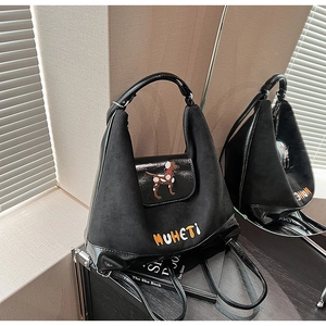 Dettaglio dello zaino hobo nero con ricamo cane colorato e trame in pelle mista
