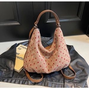 Close-up of corduroy tote bag with red polka dots and silver bow on leather jacket
