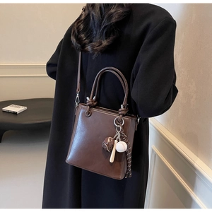 Detail of dark brown bucket bag featuring unique sports charms and smooth faux leather