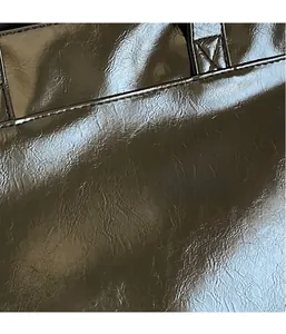 Close-up of brown oiled leather tote bag showing fine stitching and smooth glossy texture